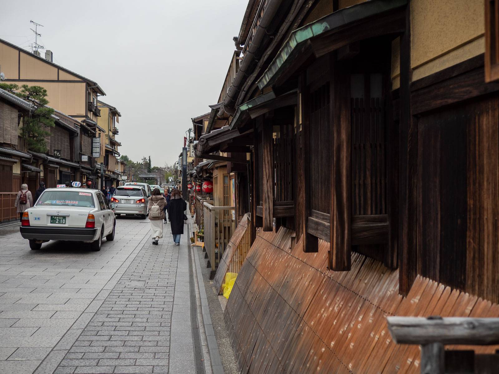 Pedestrians and cars traveling down Hanamikoji Dori
