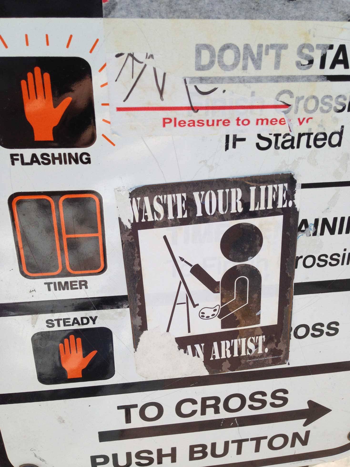 Traffic light sign with a sticker “Waste your life. Become an artist.”
